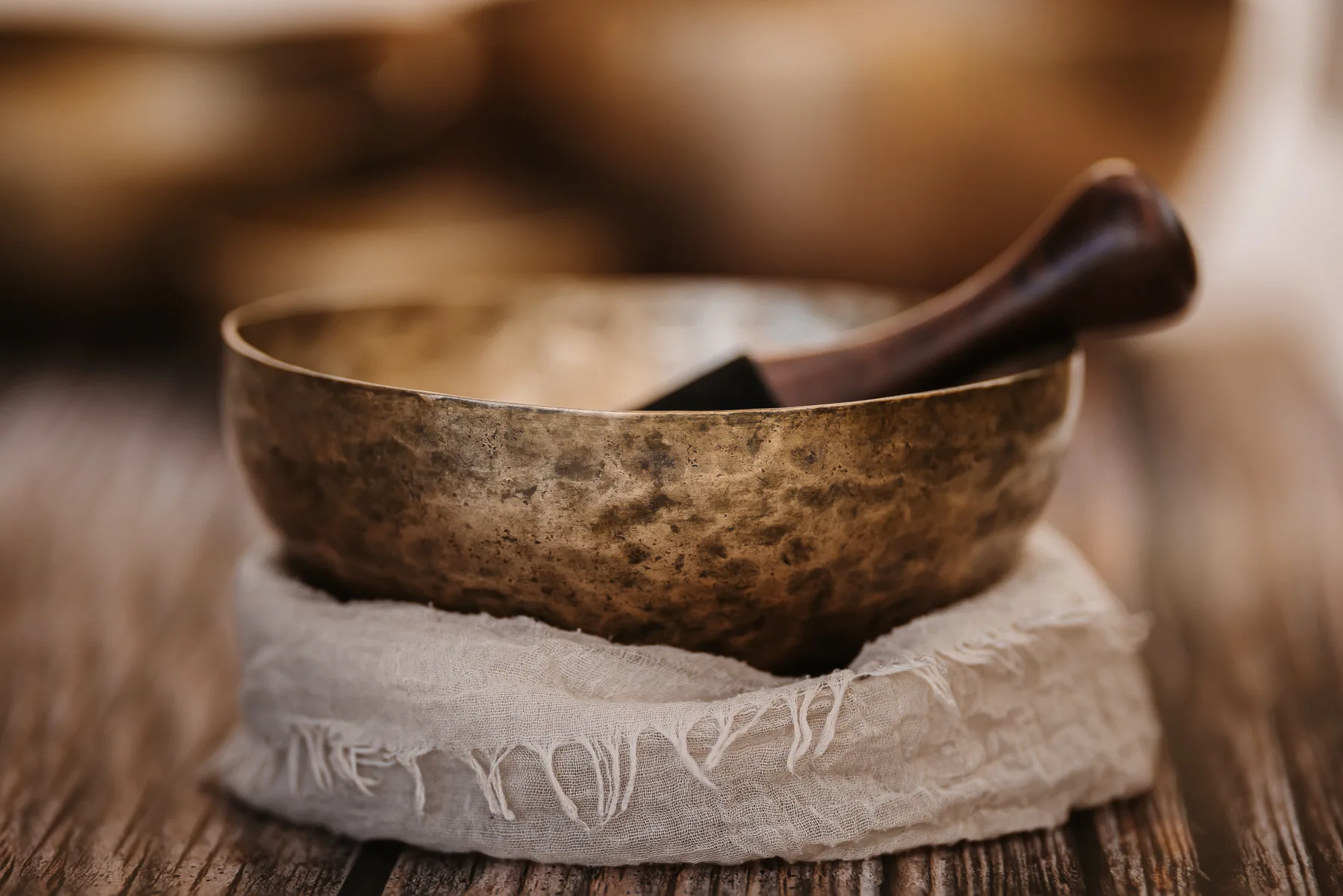 Close-up of an antique Tibetan singing bowl with mallet on a rustic wooden table