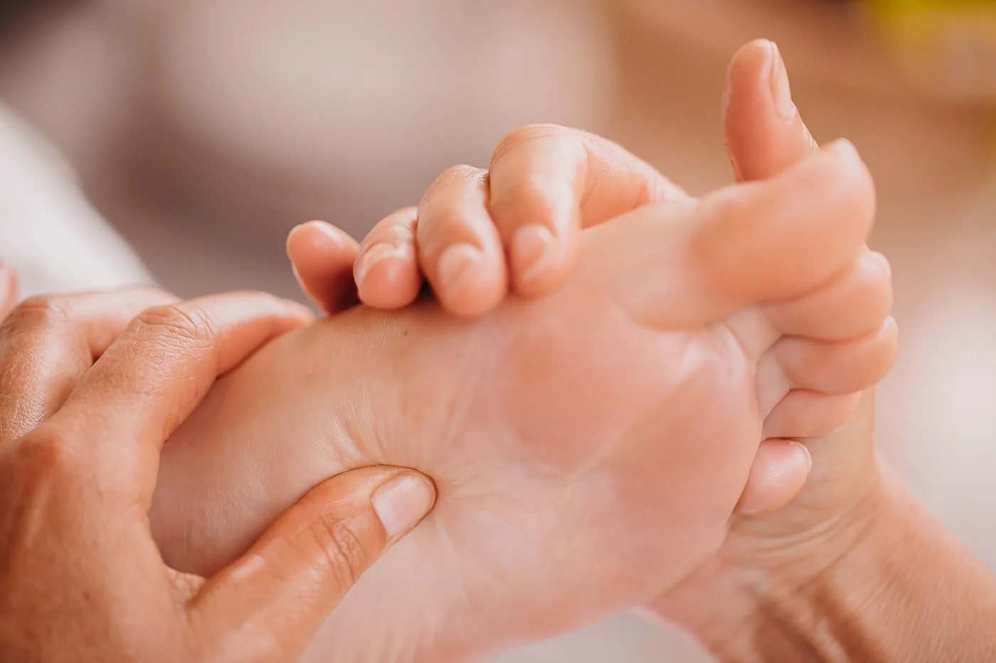 Close-up of a woman’s hands and a foot during a foot reflexology massage